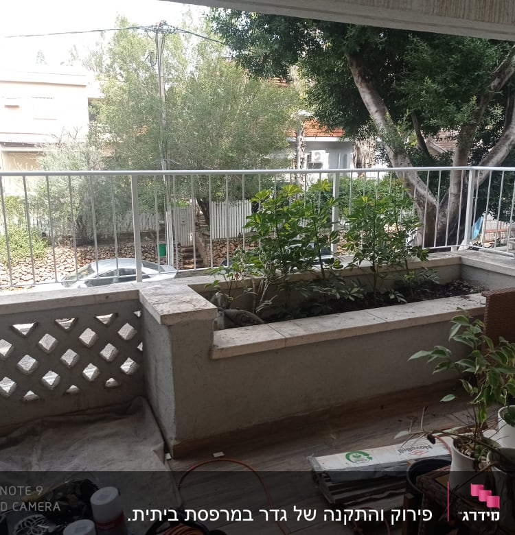 מעקה מתכת לבן במרפסת עם עציצים ירוקים